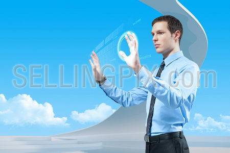 Young handsome businessman using futuristic hologram interface and keyboard in the bio style interior.